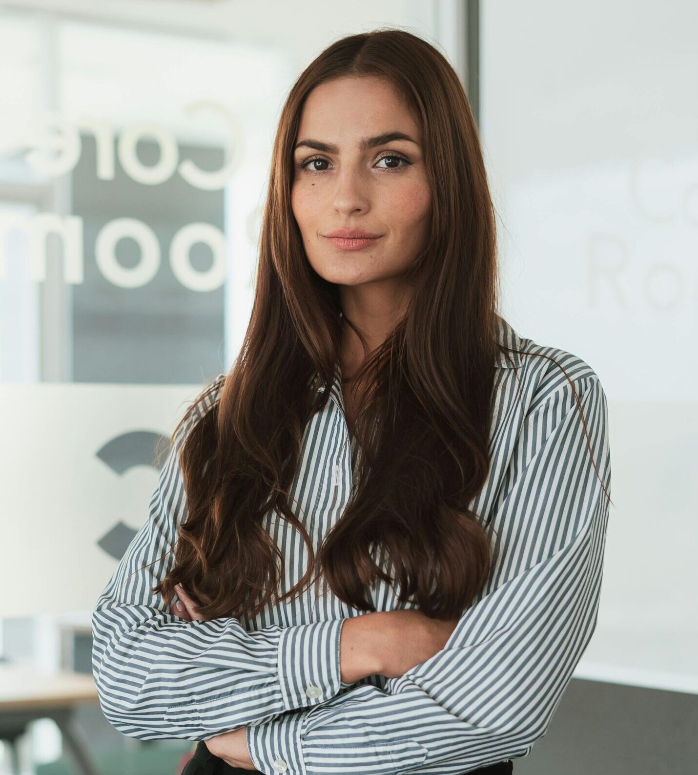 Professional woman standing confidently in a modern office environment.